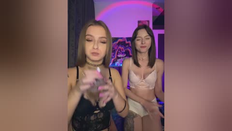 Media: Video of two young women in lingerie, one in black lace, the other in white, in a dimly lit room with purple lighting and posters.