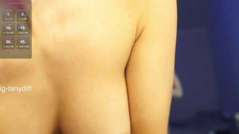Media: A video shows a fair-skinned person's bare back with a digital thermometer reading \"98.6\u00b0F\" on the left. The background is blurred, featuring a dark blue wall. The image is candid and intimate, focusing on the person's skin texture and warmth.