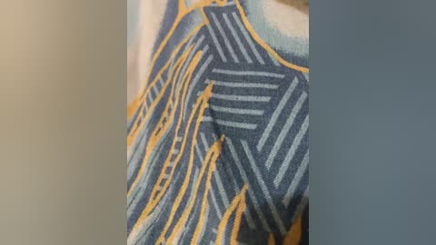 Video of a close-up of fabric featuring geometric patterns in shades of blue, yellow, and white, with a textured, woven appearance, set against a blurred background.