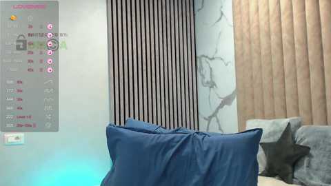 Video of a modern bedroom with a blue pillow on a gray couch, striped black-and-white wall, beige curtains, and digital clock displaying time and social media icons.