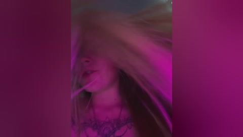Media: Video of a young woman with long, dark hair partially obscuring her face, wearing a light-colored, floral-patterned top, set against a pink, purple, and blue gradient background.
