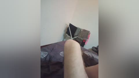 Video of a hand holding a black and white geometric patterned pillow against a white wall, capturing a minimalist bedroom setting.