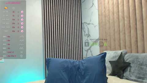 A video of a modern living room with a grey sofa, blue throw pillows, a wooden wall, and a digital calendar. The room is well-lit, featuring a mix of contemporary and minimalist decor.