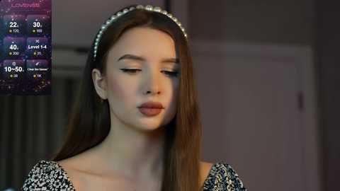 Media: A video of a young woman with fair skin, long brown hair, wearing a pearl headband and a black floral dress. The background is blurred, with a weather app overlay showing 30\u00b0C and sunny conditions.