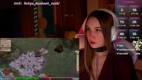 Media: Video of a young woman in a dark room, wearing a black choker and headphones, watching a game with a map on her computer screen.