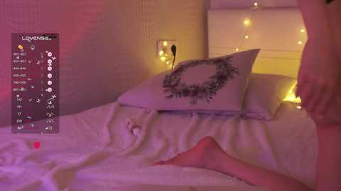 Video of a cozy bedroom with a white bed, pink sheets, a decorative pillow, and a warm yellow light backdrop.
