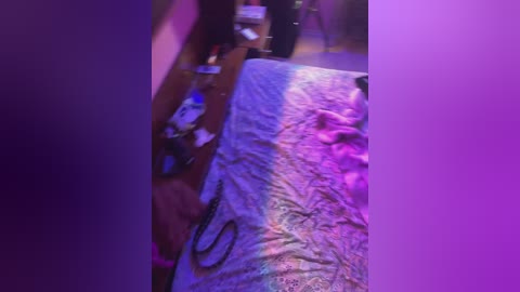 Media: A dimly lit video of a messy bedroom with a purple glow, showing a bed covered in a quilt, scattered clothes, and a person partially visible in the background.