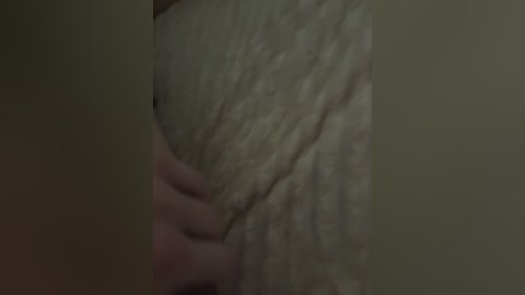 A close-up video of a woman's upper body, focusing on her large, sagging breasts and a hand gently cupping her left breast. The skin is pale and wrinkled, with a dim, muted lighting creating a somber, intimate atmosphere.