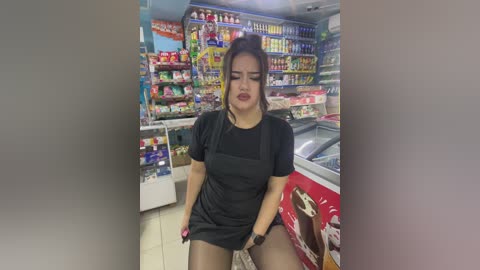 Media: Video of an Asian woman in a black dress, revealing her underwear, in a grocery store, surrounded by colorful shelves of products.