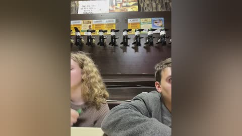 Media: Video of a man and woman, both in casual attire, seated at a diner counter with a row of toy soldiers and a menu board in the background.
