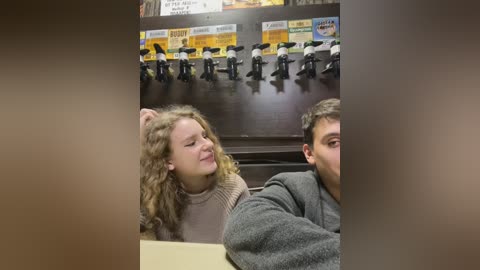 Media: Video of a young Caucasian couple, with curly-haired girl smiling, wearing a beige sweater, and a guy with short dark hair, in a restaurant booth, surrounded by toy police figures and signs.