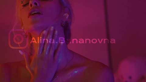 Media: Video of a woman with wet, short hair, illuminated by pink and purple lights, holding her face, with the text \"Alina Bananova\" overlaid.