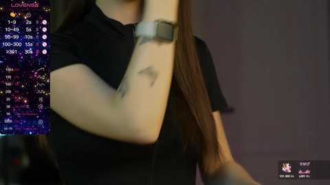 Media: Video of a woman with long brown hair, wearing a black shirt and a smartwatch. Background shows a streaming platform interface with live viewers and chat.