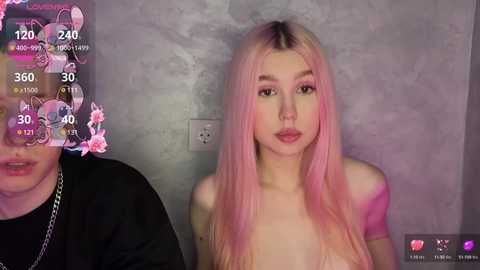 Media: Video of a fair-skinned, young woman with long, pink hair and minimal makeup, wearing a black top. Background features a gray wall and a digital overlay with temperature and humidity readings.