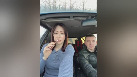 Media: A video of an Asian woman in a blue sweater, smoking in the front seat of a car, next to a Caucasian man in a green jacket, with a barren winter landscape visible outside.