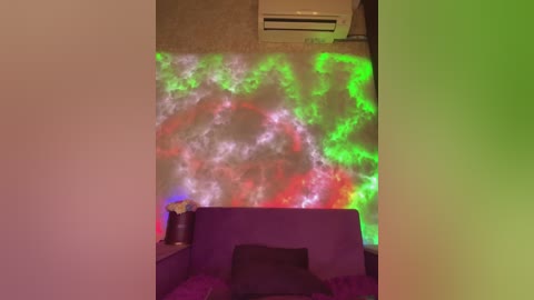 A video of a dimly lit room with a purple couch, a vase on a table, and a wall projected with vibrant green and red smoke-like patterns. An air conditioning unit is mounted on the wall.