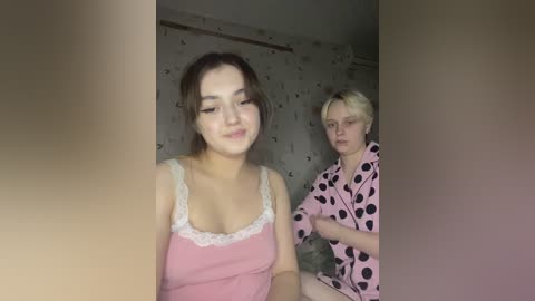 Media: Video of two women in a dimly lit room; one in a pink camisole, the other in a polka-dotted robe.