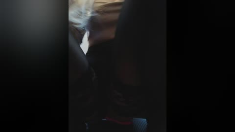 Media: A blurry, dimly-lit video showing a person with light brown hair in a black jacket, partially obscured by a shadowy figure in the foreground.