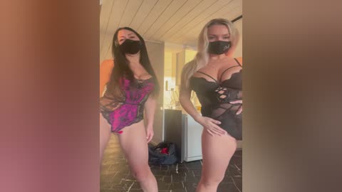 Media: Video of two women wearing black face masks, one with long black hair, the other with long blonde hair, in revealing black lingerie, standing indoors in a dimly lit room with brick walls and a wooden ceiling.