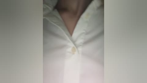 Media: A close-up video of a white, buttoned-up shirt with visible collar and chest area. The shirt is slightly wrinkled and the buttons are yellow. The background is plain and out of focus.