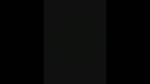 A video with a dark, monochromatic aesthetic, featuring a vertical black rectangle centered against a pitch-black background. The image's minimalist style creates a stark contrast, emphasizing simplicity and abstraction.