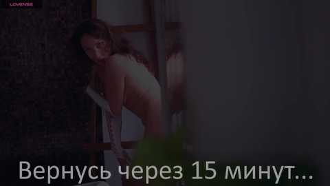 Media: Video of a naked woman with curly hair, leaning against a wooden ladder in a dimly lit room. Russian text at the bottom.