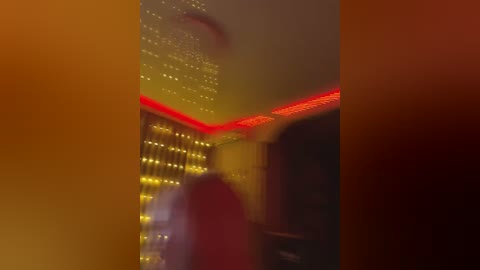 Media: A video of a dimly-lit room with red LED strip lighting on the ceiling and walls, creating an eerie ambiance. A person, blurred, is seen in the background, possibly moving.