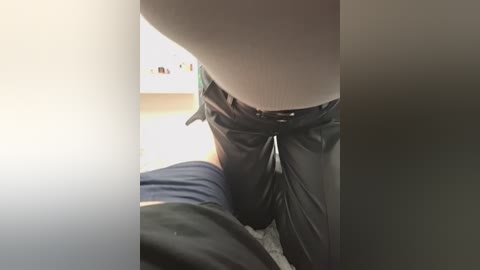 A video captures a person in black pants and a blue shirt kneeling on a white bed, with a blurry background. The image is slightly grainy and has a warm, soft lighting.