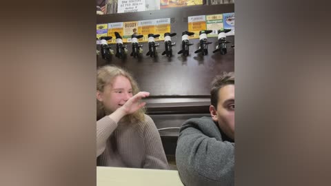 Media: A video of two people at a restaurant booth; a woman with curly hair and a man with short hair, both wearing casual clothing, laughing. A row of beer taps and a colorful menu board are in the background.