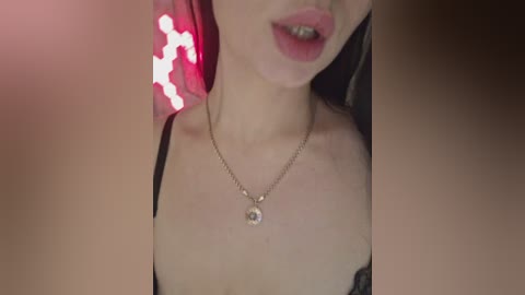 A close-up video of a woman with fair skin, wearing a black lace bra, a gold necklace, and red lipstick. The background features a blurred, lit-up heart shape.