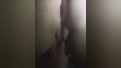 A dimly lit, close-up video of a woman's vulva with slightly parted labia, revealing the inner folds and clitoral hood. The image has a soft, natural lighting, highlighting the textures and contours of the skin.