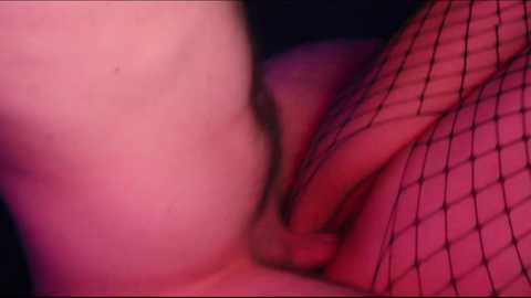 A close-up, soft-focus video featuring a person's exposed buttocks and thighs, partially covered by black fishnet stockings. The skin is pale, and the background is dimly lit, creating a sensual, intimate atmosphere.