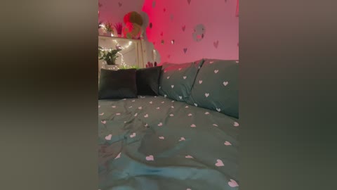 Video of a cozy bedroom with a dark green bedspread adorned with small pink hearts. Pink wall decor includes a large floral arrangement and heart-shaped stickers. Soft, ambient lighting creates a warm, romantic atmosphere.