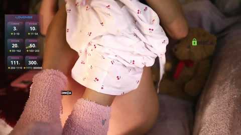 Media: Video of a toddler in a white, patterned dress with a teddy bear on a bed, overlaying a digital graph displaying heart rate data and other health metrics.