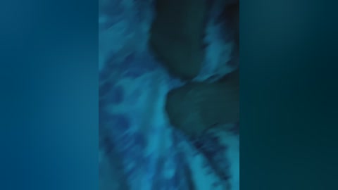 A video of two dark-skinned people embracing in a shallow pool of water. The water is a mix of blue and white hues, creating a serene and intimate atmosphere. The background is blurred, focusing attention on the couple.