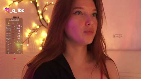 Video of a young Caucasian woman with fair skin and long, straight brown hair, wearing a black top, standing in a warmly lit room with a string of yellow lights and a \"TikTok\" watermark in the corner.