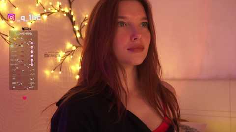 Video of a young woman with long, straight brown hair, wearing a black jacket and red top, standing in a softly lit room with warm, yellow string lights and a 'Instagram' app interface visible in the background.