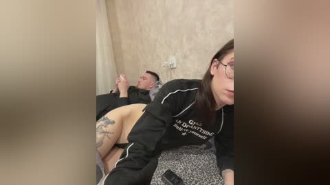 Media: A video shows a tattooed man lying on a hospital bed, with a woman wearing glasses and a black top sitting beside him.
