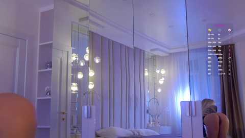 Video of a modern bedroom with mirrored walls, soft lighting, and a person facing away from the camera.