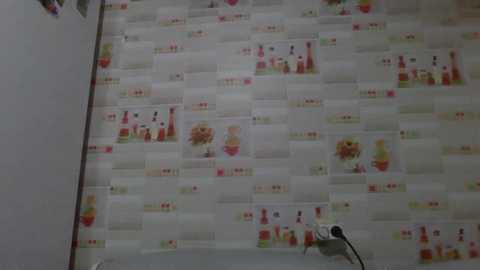 Video of a bathroom wall with a tiled design featuring small, colorful images of bottles and flowers on a white background. The tiles are small and uniform, creating a mosaic-like effect.