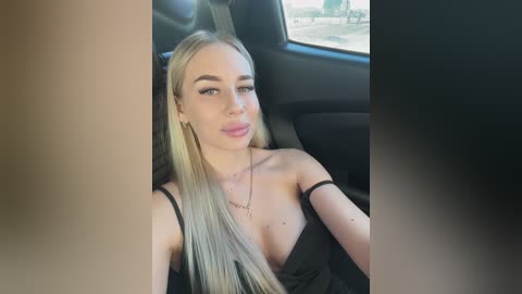 Video of a young blonde woman with fair skin, wearing a black dress, sitting in a car, looking confident and poised.