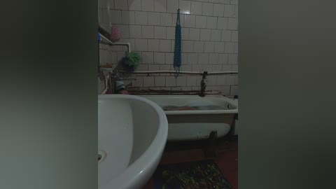 A dimly lit, old bathroom with a white ceramic sink, a tiled wall, a blue towel hanging, and a bathtub. The scene is slightly blurred, giving a sense of mystery.