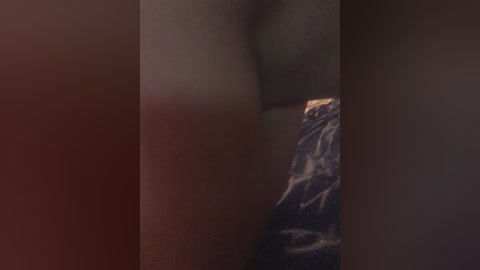 Video of a close-up view of a person's arm and hand wearing a dark blue, patterned shirt, with blurred background.