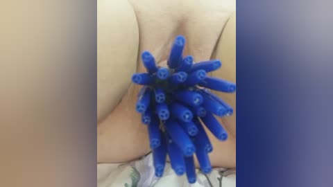 Video of a person's torso with a cluster of blue, plastic, skeleton-shaped ice cubes resting on their bare skin, creating a striking contrast against their light skin tone.