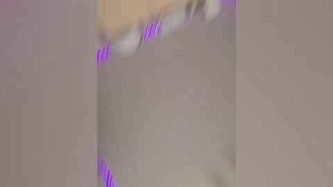 A close-up video of a woman's face with blurred features and purple lipstick, creating a soft focus effect. The background is a muted, neutral color, emphasizing the lips and mouth.
