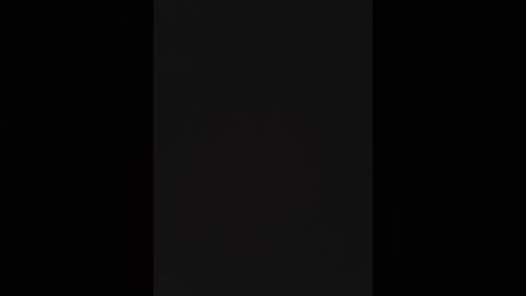 This image is a video of a black-and-white striped flag against a dark background, with no other objects or people visible. The flag's stripes are evenly spaced, creating a stark, minimalist design.