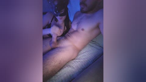 Media: A dimly lit video captures a close-up of a nude woman and man engaged in sexual activity, with the man's erect penis visible. The woman has medium skin tone and dark hair, and the man has a light skin tone.