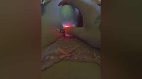 Video of a close-up view of a woman's vagina, showing a green vibrator with red light emitting from the tip, inserted into her pink lace underwear.