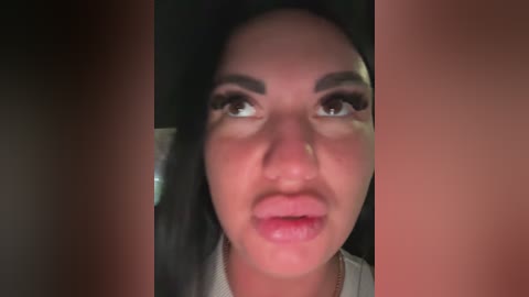 A video of a woman with long black hair, brown eyes, and light skin, wearing makeup, taken from a close-up angle.