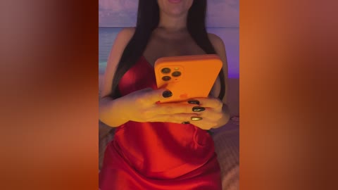 Video of a woman with long black hair, wearing a red satin dress, holding an orange phone, nails painted black, indoors with a purple and orange background.